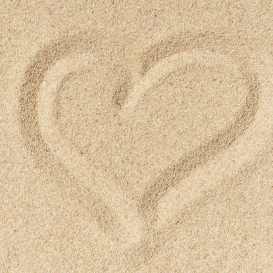 Heart sand beach texture background. Light hot sand on the sea coast in summer. Travel, relax, vacation concept. High quality photo